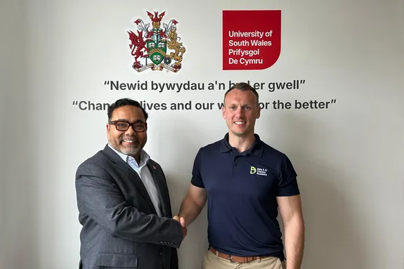 Representatives from the University of South Wales and the Data & AI Literacy Academy shake hands to mark a partnership.