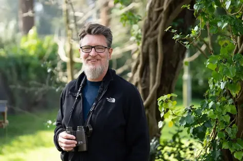 Dr David Lee standing in a garden next to a tree