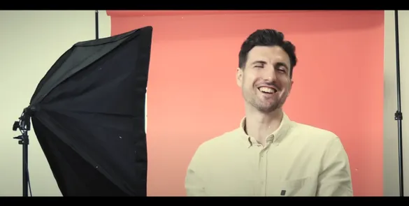 A member of the student recruitment team sat in front of a red backdrop, laughing.