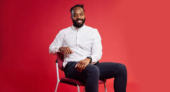 Lecturer sat in front of a red backdrop