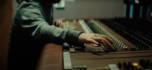 A students hand moving buttons on recording equipment