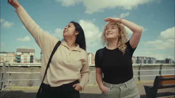 two students outside of Newport campus both looking off into the distance