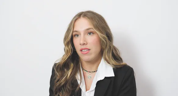 Student, Charlotte, is sat in front of a white wall, talking to the camera.