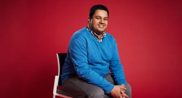 Course leader sat in front of a red backdrop smiling