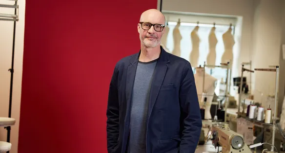 Staff stood in front of red backdrop in a fashion studio smiling