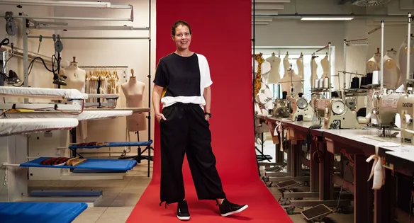 Member of staff stood in front of a red backdrop in the fashion studios