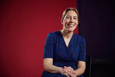 Staff sat in front of red backdrop smiling
