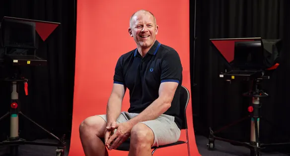 Staff sat in front of a red backdrop smiling