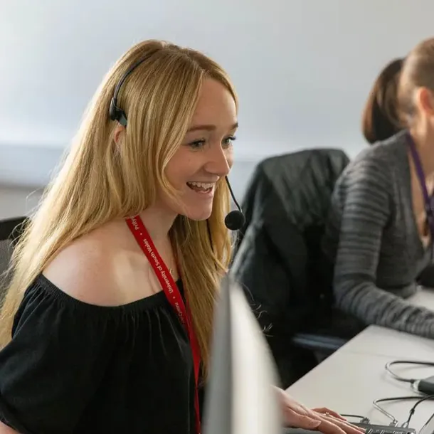 A USW staff member is smiling whilst taking a call via a headset.