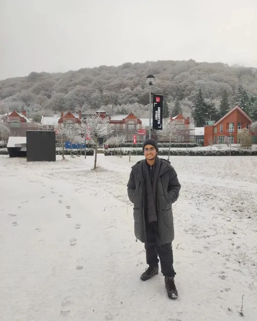 A student standing in front of Glyntaff campus in the snow