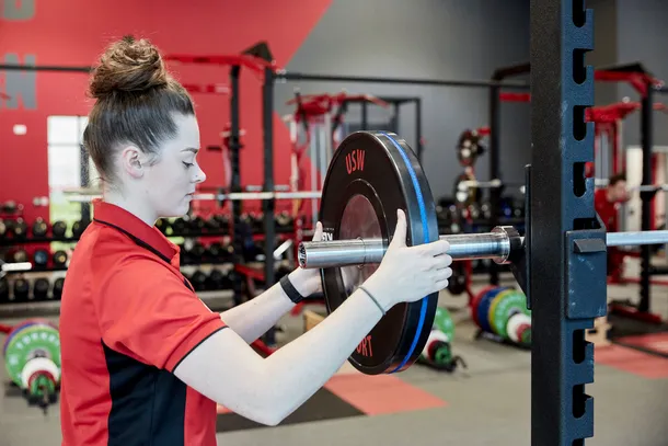 Female Sport student adding weight to a lifting platform.