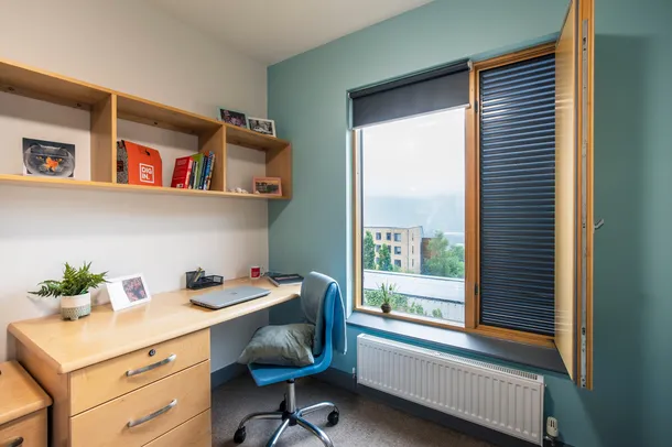 A desk and shelving unit next to a large window at Mountain Halls, Pontypridd.