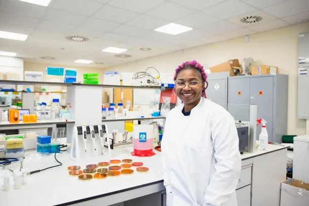 Talatu Usar, Postgraduate Research Student, standing in a lab smiling to camera