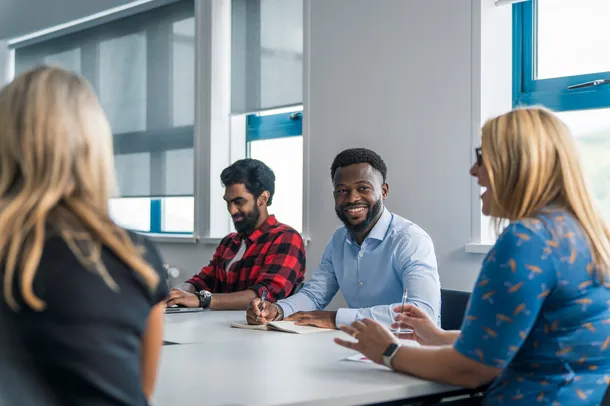 four members of university staff working and having a conversation, smiling