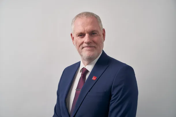A profressional photograph of Ben Calvert smiling at the camera.