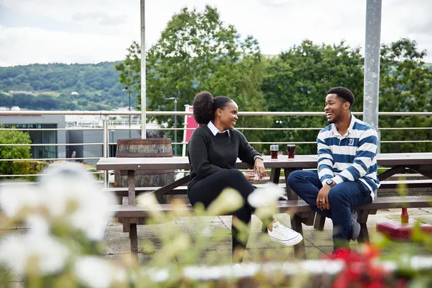 2 students sat outside the student's union in Treforest enjoying a drink