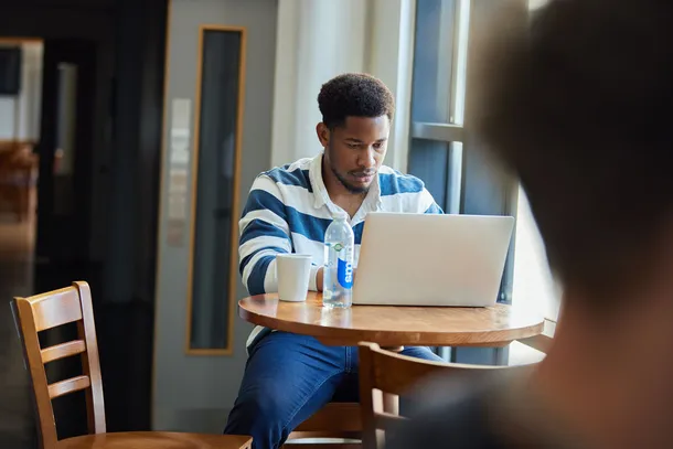 student working at a laptop in the students union at Pontypridd campus, Treforest