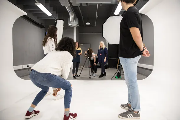 A lecturer is supervising a lesson, while students set up a professional photoshoot.