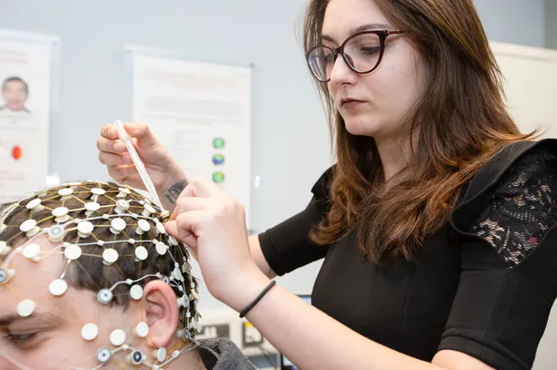 A student is placing a brain cap onto another students head.