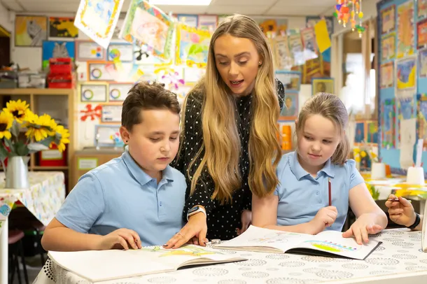 USW student on placement, supervising two children colouring in  Art classroom.