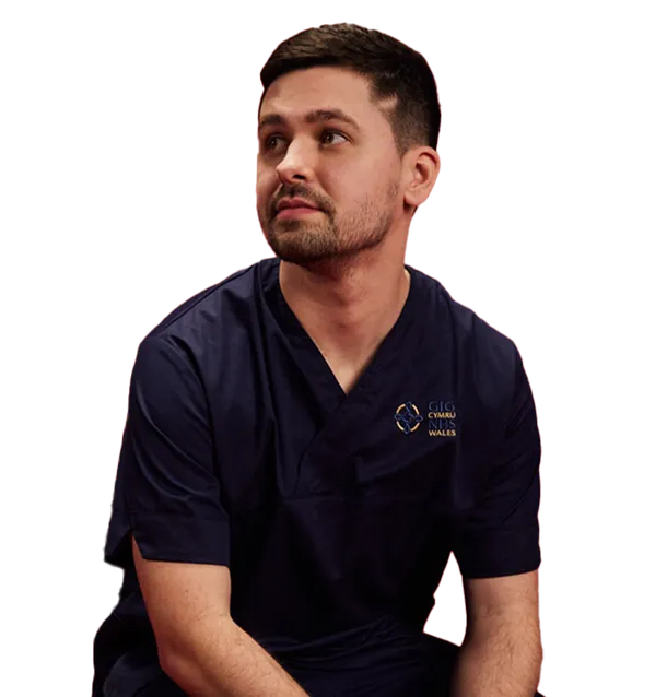 Nursing graduate, Patrick, sat in scrubs and looking away from the camera.
