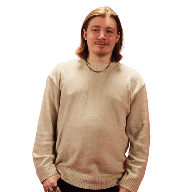 Cyber Security graduate, Sam, is stood smiling at the camera with his hands in his pockets.