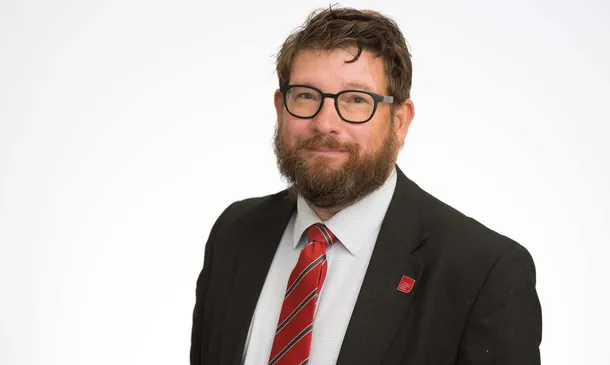 Professor Martin Steggall smiling at the camera in front of a white backdrop