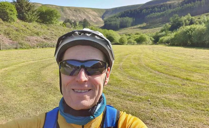 A selfie of Tim Morris in a sunny green field.