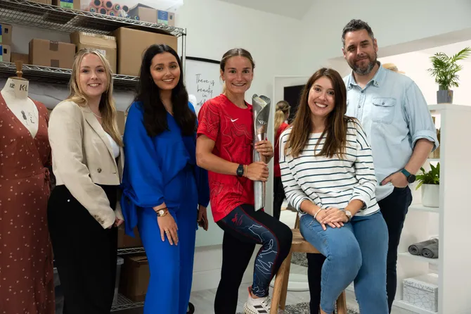 olivia soady, bethan jones and steven wright of usw, gabriella diana of onesta and team wales athlete posing with commonwealth games trophy wearing leggings designed by usw students