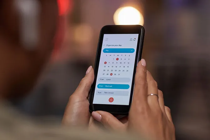 Close-up of woman using online calendar on mobile phone to plan her week