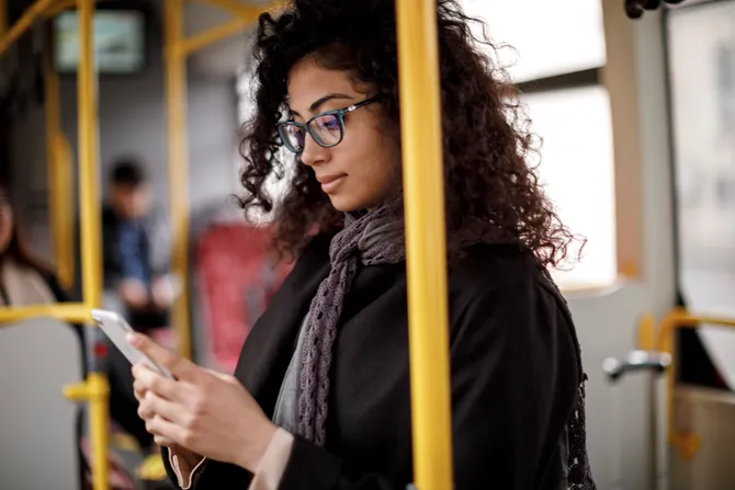 A person stood using their phone on a bus.