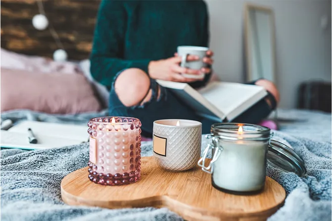 A student relaxing at home, reading a book with a scented candle