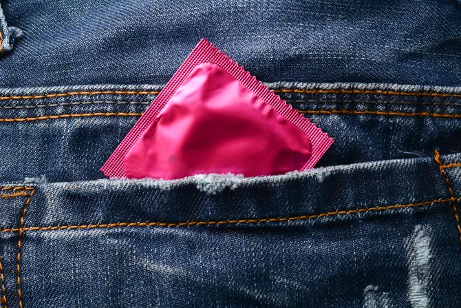 pink condom poking out of the pocket of a pair of jeans