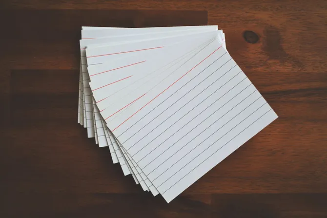 A pile of blank lined cards spread out on a wooden table.