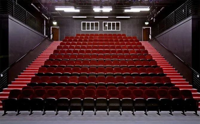 Red seats tired from the front of the stage to the top back wall in the Cardiff campus theatre