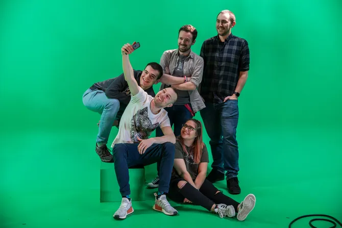 A group of students taking a selfie in front of a green screen.