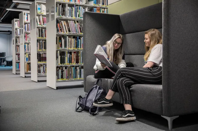 Students sitting in a study pod in the Cardiff campus library.