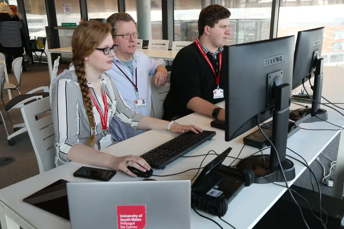 Students and a lecturer sat in front of computer screens, working.