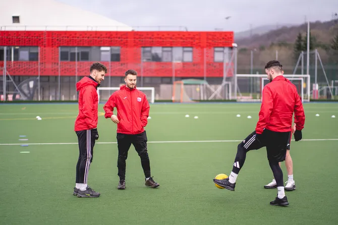 USW Sport students kicking a football on the outdoor pitch.