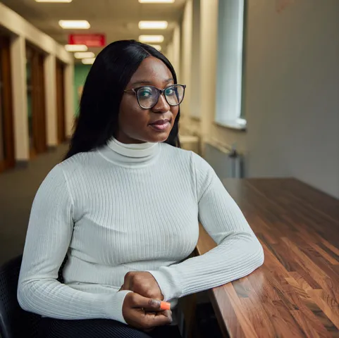 A student sat at a table and smiling at the camera in the postgraduate centre.
