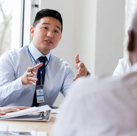 An over the shoulder shot of two men in businesswear having a conversation in an office.