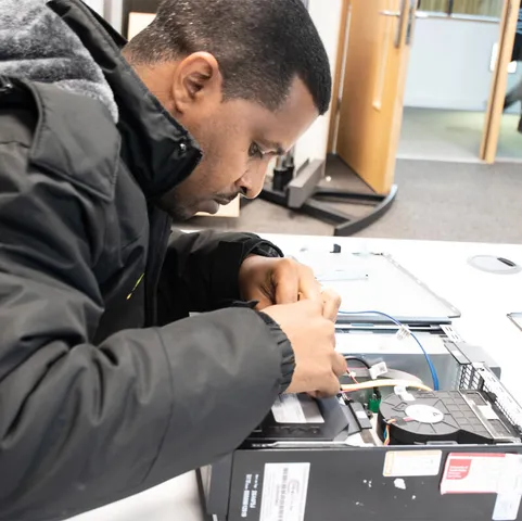 A student fixes the inside of a desktop computer
