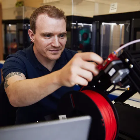 A student concentrates while using a piece of mechanical equipment in an engineering workshop