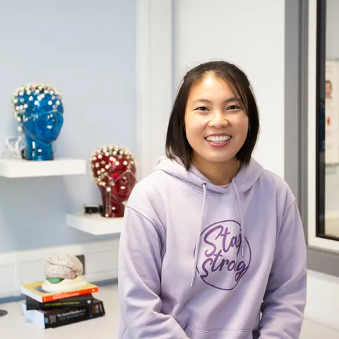 A student smiling at the camera amongst psychology lab equipment