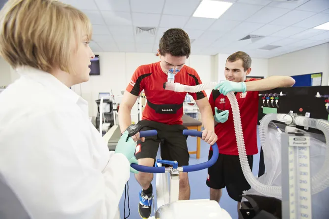 A group of sport science students are measuring oxygen output from a student on a stationary bike.