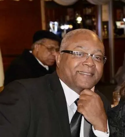 Carl Connikie smiles at the camera while dressed in a suit at a black tie function