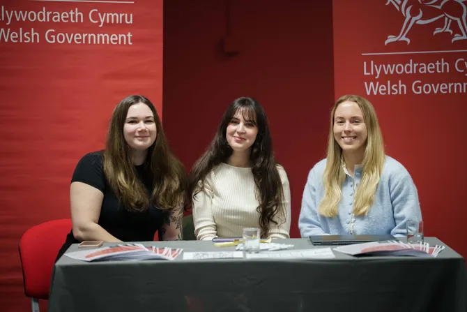 Employers from the Welsh Government sat at a stall at our Graduate Futures event, smiling at the camera.