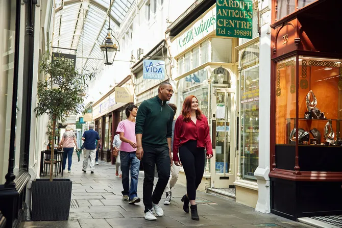 A group of students walking through a Cardiff arcade.
