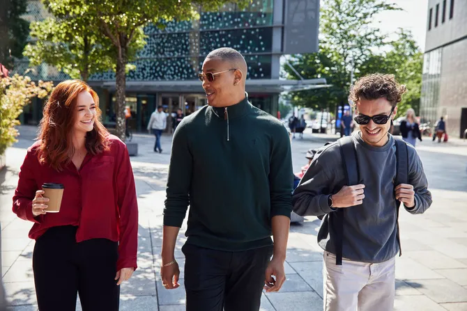 A group of students walking down through Cardiff holding coffee.