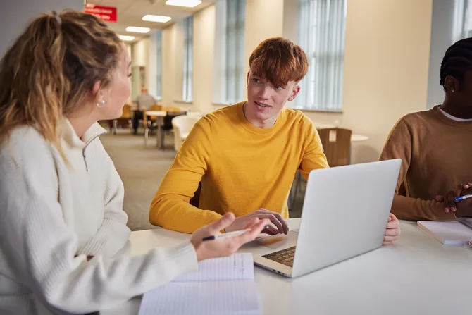 Students studying on a laptop and talking.